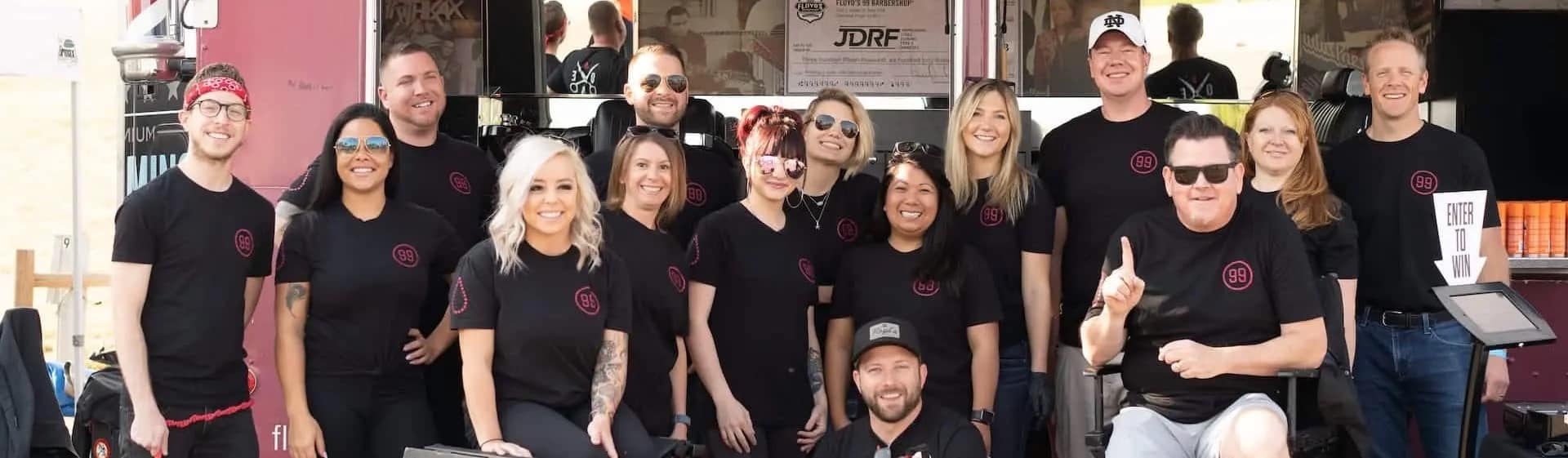 Floyds's 99 Barbershop team members smiling in front of a shop.